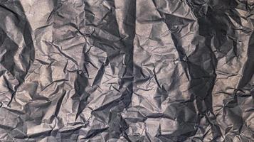 The black paper background is wrinkled, creating a rough texture with light and shadow. photo