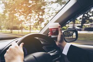 Man driving car while holding a cup of coffee photo