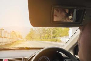 Woman makeup her face using blush brush while driving car, unsafe behavior photo