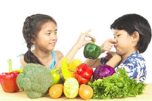 Asian boy and girl showing dislike expression  with fresh colorful vegetables isolated over white background photo