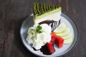 Colorful green tea favor cake with well decorated fruit pieces and whipped cream in white plate - cake recipe menu concept photo