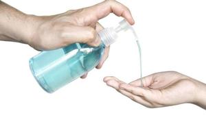 Closeup of father hand pushing alcohol sanitizer gel pump dispenser to son hand isolated over white background - people with alcohol sanitizer prevent bacteria and COVID-19 virus protection concept. photo