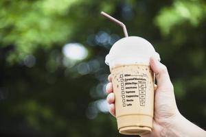 mano que muestra una taza de café con hielo fresco - refresco con el concepto de fondo de una taza de café con hielo foto