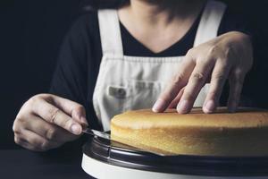 señora haciendo pastel poniendo crema con espátula - concepto de cocina de panadería casera foto