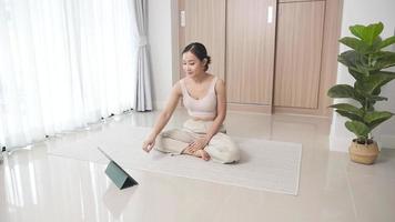 entrenamiento de entrenamiento de yoga de fitness deportivo en línea. mujer joven y haciendo ejercicios frente a la computadora portátil en casa. yoga asanas mujer practicando yoga concepto equilibrio natural entre el cuerpo y el desarrollo mental. video