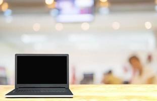 Laptop on white wooden table top over blurred business customer service room with some of people photo