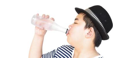 Un niño de 14 años está bebiendo una botella de agua fresca y fría aislada en blanco foto