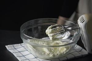 señora haciendo pastel poniendo crema con espátula - concepto de cocina de panadería casera foto