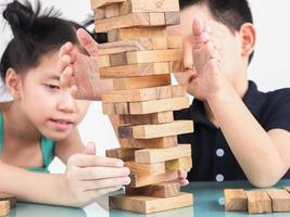 los niños juegan jenga, un juego de torre de bloques de madera para practicar su habilidad física y mental foto