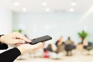 A man is using telephone over blurred bokeh light in office and people background photo