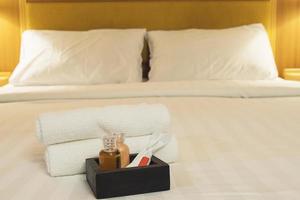 Hotel towel set with toothbrush and toothpaste on white bed photo