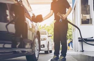 el hombre está poniendo ngv, vehículo de gas natural, dispensador de cabeza a un automóvil en la estación de gasolina en tailandia foto