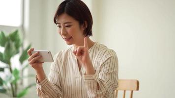 eine frau, die fingerbuchstaben der japanischen gebärdensprache auf ihrem smartphone studiert video