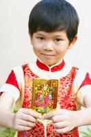 el niño muestra felizmente su sobre de regalo de dinero en el festival del año nuevo chino. la foto se centra en el sobre.