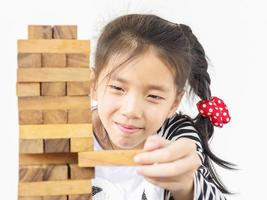 un niño asiático está jugando jenga, un juego de torre de bloques de madera para practicar habilidades físicas y mentales foto