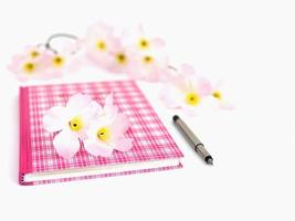 diario rosa dulce con pluma y flor artificial, enfocado selectivamente y aislado sobre blanco foto