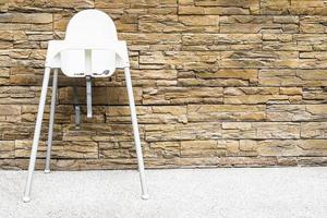 Baby chair with sand stone wall background photo