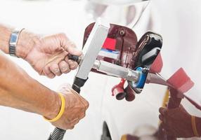 Man is putting NGV, Natural Gas Vehicle, head dispenser to a car at the gasoline station in Thailand photo