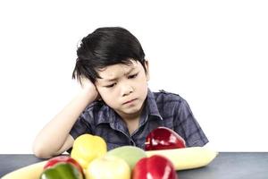 Asian boy is showing dislike vegetable expression over white background photo