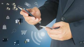 Businessman is using mobile phone and holding credit card with shopping icons overlay - online shopping concept photo