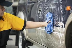 El hombre lava el coche con champú - concepto de cuidado del coche de la vida cotidiana foto