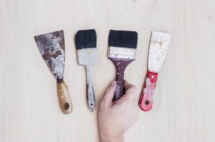 Old painting hand tools with hand over wooden background photo