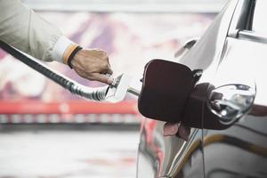 el hombre está poniendo ngv, vehículo de gas natural, dispensador de cabeza a un automóvil en la estación de gasolina en tailandia foto