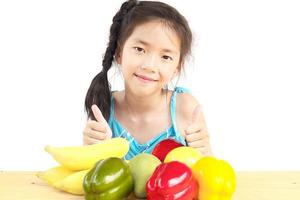 Gril asiático saludable mostrando expresión feliz con variedad de frutas y verduras de colores sobre fondo blanco. foto