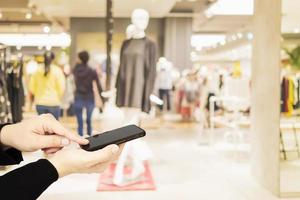 Man using mobile phone over blurred superstore background photo