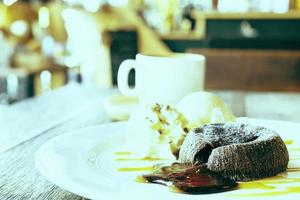 foto antigua de pastel de lava de chocolate en un plato blanco con una taza de café en una cafetería