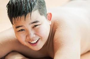 A boy is happily playing with sprayed water during hot season photo