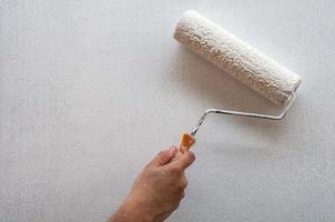 Hand holding rolling paint brush, wall painting photo