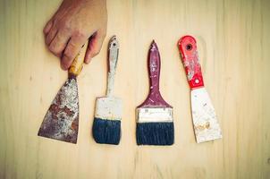 Old painting hand tools with hand over wooden background photo