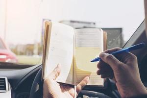 Man writing notebook while driving car, dangerous behavior photo