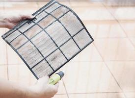 Air conditioner maintenance man cleaning  cover during hot season in Thailand photo