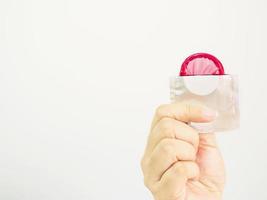 Lady's hand showing red condom and package with white copy space background photo