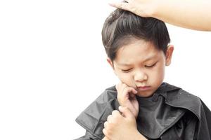 A boy is feeling itchy while cutting his hair by hair dresser isolated over white background photo