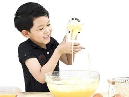 un niño está haciendo pastel aislado sobre blanco. la foto está enfocada en su rostro.