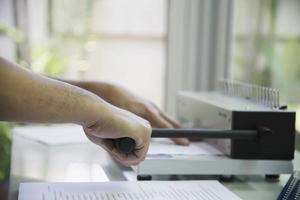 Man making report using comb binding machine - people working with stationary tools concept photo