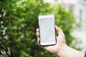 Man holding broken mobile with damaged display photo