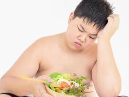 un chico gordo odia comer ensalada de verduras foto