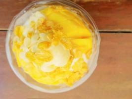 Top view of snow ice cream with mango and cornflakes topping on wooden table photo