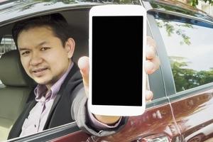 Driver is showing mobile phone with black blank screen while sitting in a car. Photo is focused at mobile screen and includes CLIPPING PATH for mobile screen.
