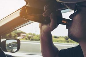 Man drinking beer while driving a car photo