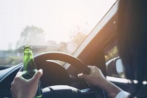 Woman holding beer bottle while driving a car photo