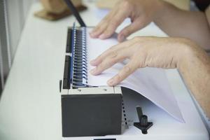 Man making report using comb binding machine - people working with stationary tools concept photo