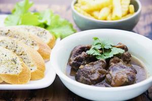 Beef and pork stew with French fries and others food recipes on wooden table, food meal preparing ready for eat concept photo