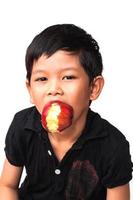 Retrato de niño feliz comiendo manzana sobre fondo blanco. foto