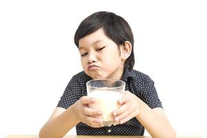 Asian boy is showing dislike drinking milk expression over white background photo