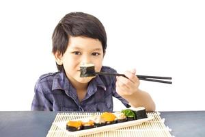 Chico encantador asiático está comiendo sushi aislado sobre fondo blanco. foto